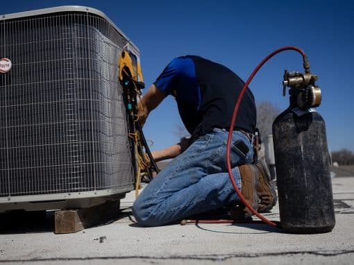 Technician checking an outdoor AC unit with gauges